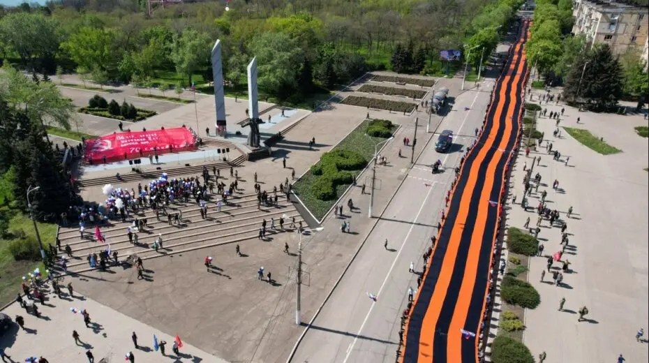 Participants hold a giant St. George's Ribbon during a ceremony, marking the 77th anniversary of the victory over Nazi Germany in World War Two, in the course of Ukraine-Russia conflict in the southern port city of Mariupol, Ukraine May 9, 2022. Picture taken with a drone. REUTERS/Pavel Klimov - RC2L3U99YLY3